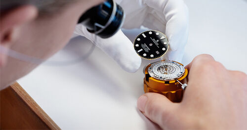 A Rolex watchmaker removing a dial